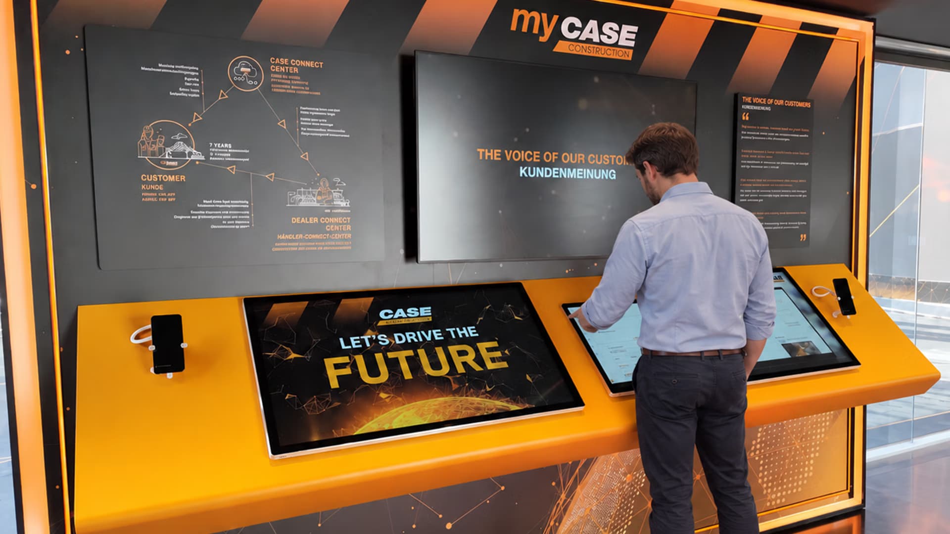 Visitatore davanti a un touchscreen in uno stand CASE interattivo con la scritta «Let's drive the future»